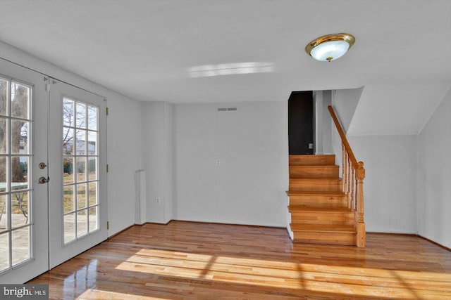 unfurnished room featuring visible vents, stairway, wood finished floors, and french doors