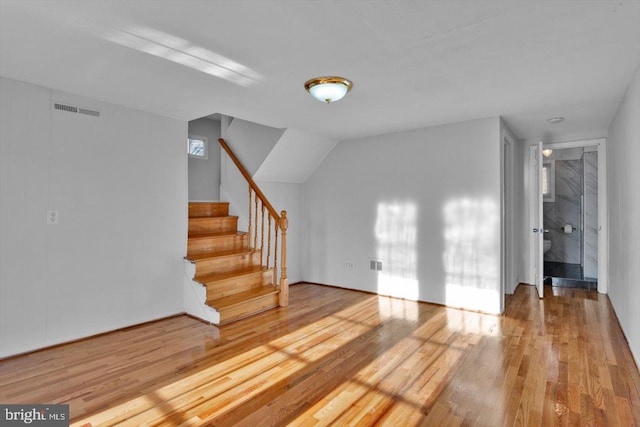 unfurnished living room featuring stairway, wood finished floors, and visible vents