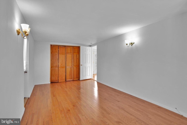 unfurnished bedroom with light wood finished floors, baseboards, and a closet