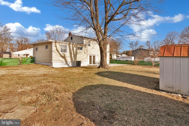 view of yard featuring french doors, an outdoor structure, a storage unit, and fence