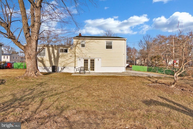 back of house featuring french doors, a patio area, a lawn, and a chimney