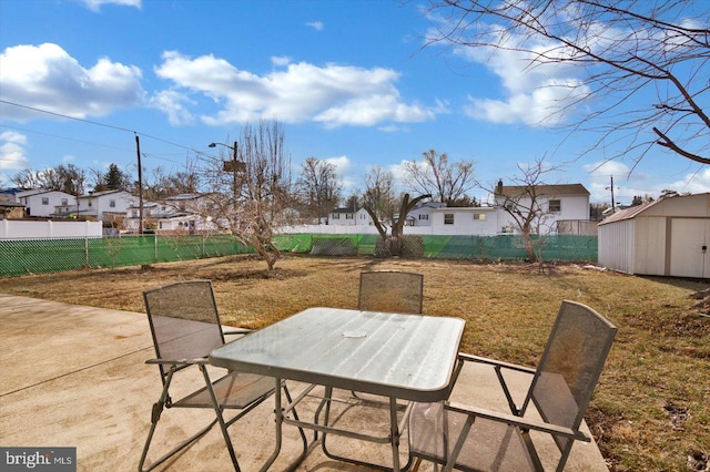 view of patio / terrace featuring outdoor dining area, a fenced backyard, an outdoor structure, and a storage unit