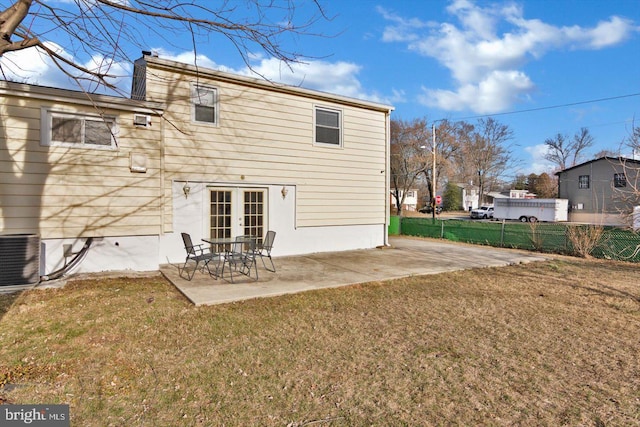 rear view of property with cooling unit, fence, french doors, a lawn, and a patio area