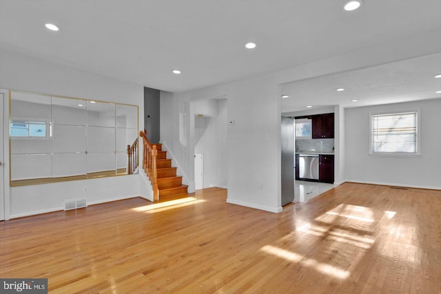 unfurnished living room featuring stairs, light wood-type flooring, visible vents, and recessed lighting