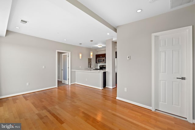 unfurnished living room featuring light wood-type flooring and sink