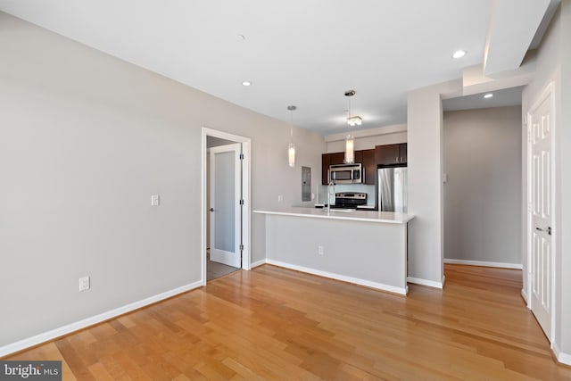 kitchen featuring kitchen peninsula, dark brown cabinets, light hardwood / wood-style floors, and appliances with stainless steel finishes