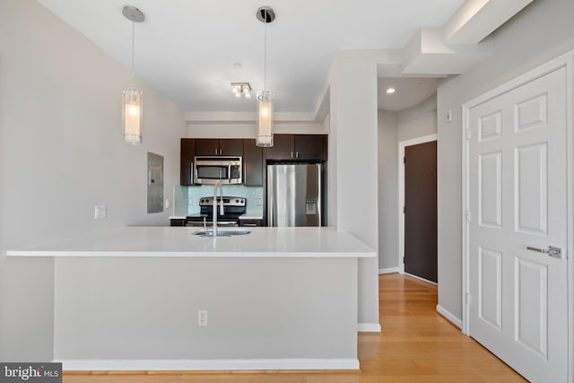 kitchen with kitchen peninsula, decorative backsplash, dark brown cabinets, and stainless steel appliances