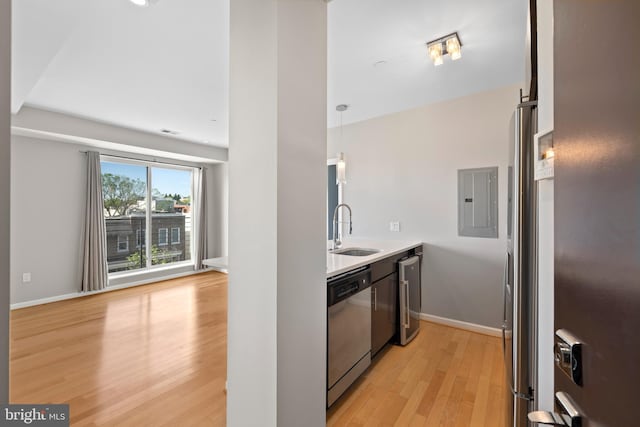 kitchen featuring pendant lighting, electric panel, sink, light hardwood / wood-style flooring, and appliances with stainless steel finishes