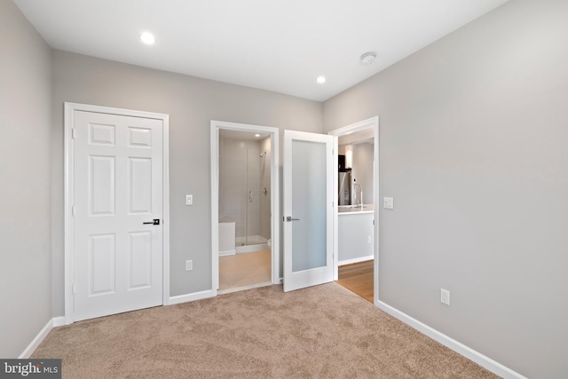 unfurnished bedroom with light carpet and ensuite bathroom