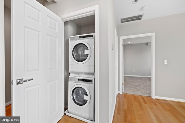 laundry room featuring light hardwood / wood-style floors and stacked washer and clothes dryer