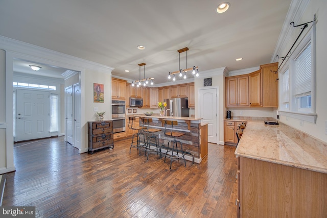 kitchen featuring a kitchen bar, dark hardwood / wood-style flooring, stainless steel appliances, crown molding, and a center island with sink