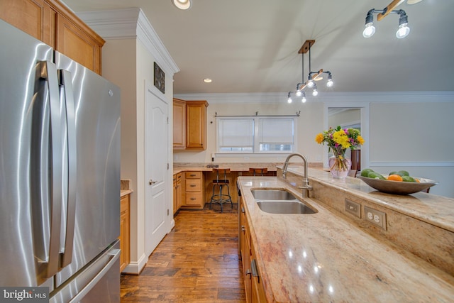 kitchen featuring light stone countertops, stainless steel fridge, decorative light fixtures, and sink