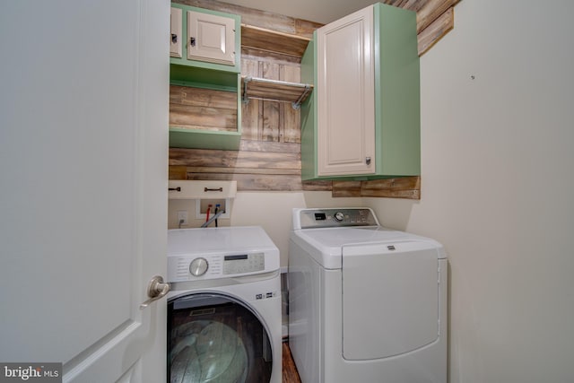 laundry room featuring cabinets, separate washer and dryer, and wooden walls