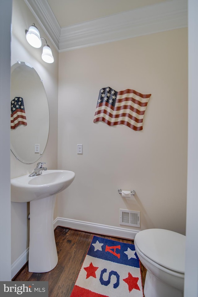 bathroom with hardwood / wood-style floors, toilet, and crown molding