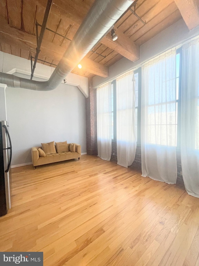 interior space featuring beamed ceiling, light hardwood / wood-style floors, and a healthy amount of sunlight