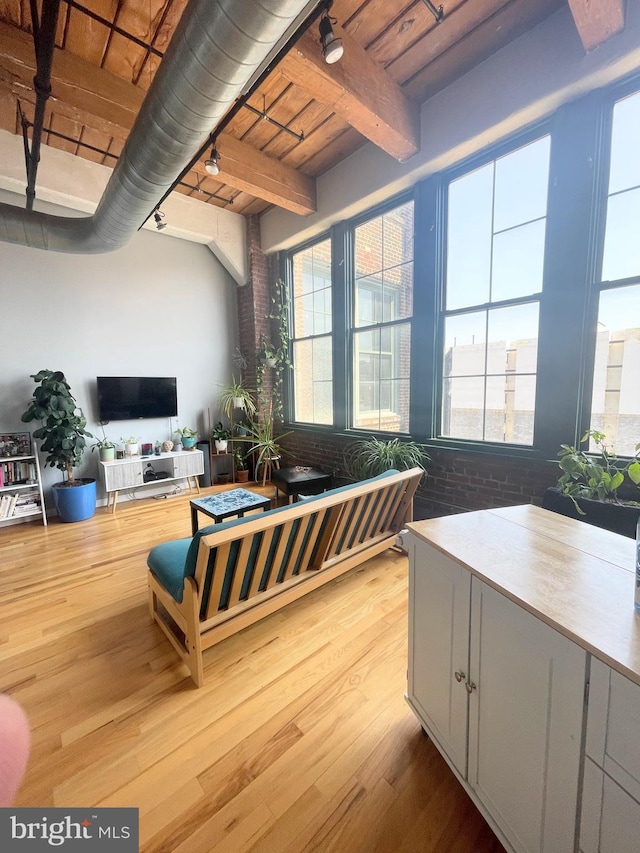 living room featuring beamed ceiling, light hardwood / wood-style floors, plenty of natural light, and wood ceiling