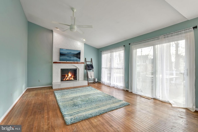 unfurnished living room with hardwood / wood-style floors, a large fireplace, ceiling fan, and lofted ceiling