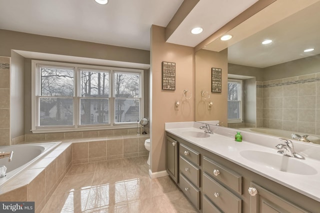 bathroom featuring tile patterned floors, tiled tub, vanity, and toilet