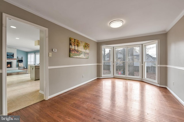 unfurnished room featuring a large fireplace, light hardwood / wood-style floors, and ornamental molding