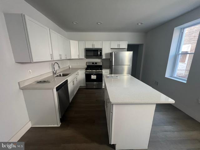 kitchen with sink, a kitchen island, dark hardwood / wood-style floors, white cabinets, and appliances with stainless steel finishes