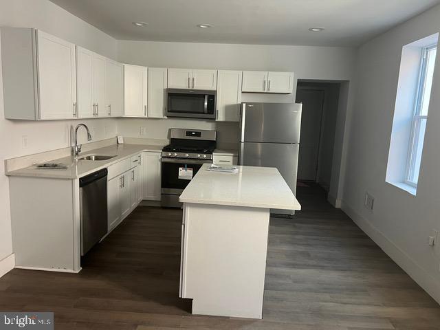 kitchen featuring stainless steel appliances, a kitchen island, and white cabinetry