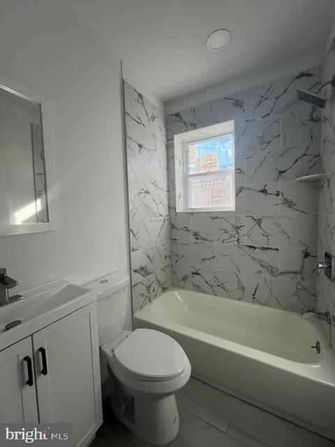 full bathroom with tiled shower / bath combo, toilet, and vanity