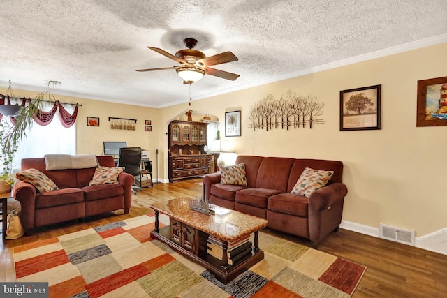 living room featuring ceiling fan, wood-type flooring, a textured ceiling, and ornamental molding