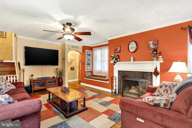 living room with crown molding, hardwood / wood-style floors, ceiling fan, and a textured ceiling