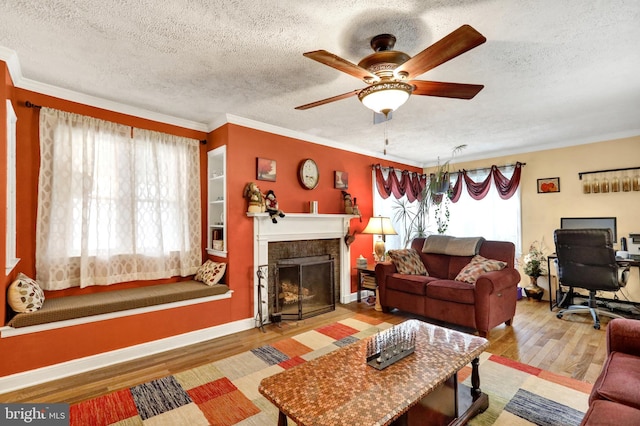 living room featuring a textured ceiling, light wood-type flooring, ceiling fan, and ornamental molding