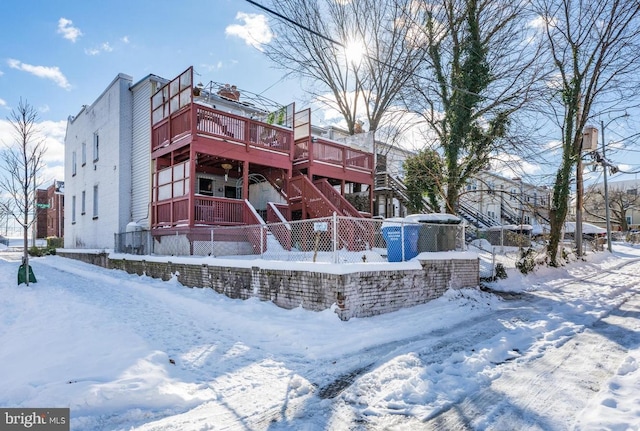 snow covered rear of property featuring a deck