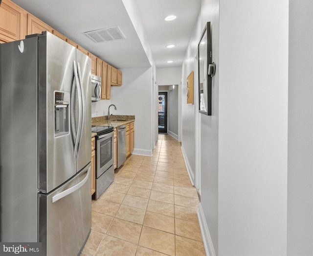 kitchen featuring dark stone countertops, sink, light tile patterned flooring, and appliances with stainless steel finishes