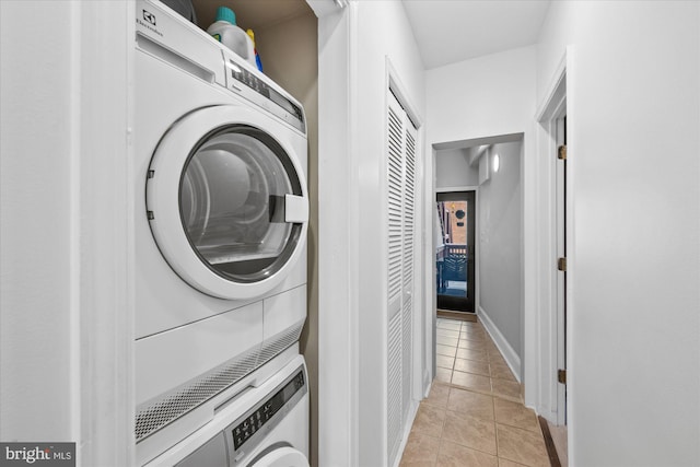 clothes washing area with light tile patterned floors and stacked washer / dryer