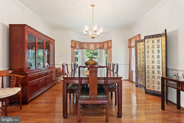 dining area with light wood-type flooring, crown molding, and a chandelier