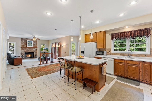 kitchen featuring a center island, white appliances, sink, a fireplace, and tasteful backsplash