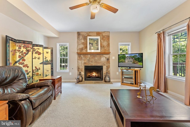 living room with a fireplace, light colored carpet, and ceiling fan