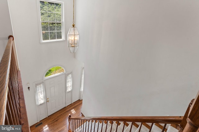 entryway featuring hardwood / wood-style flooring, plenty of natural light, a high ceiling, and an inviting chandelier