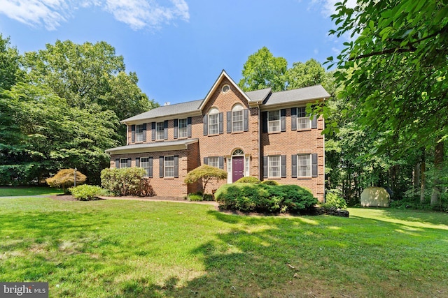 colonial inspired home with a front yard and a storage unit