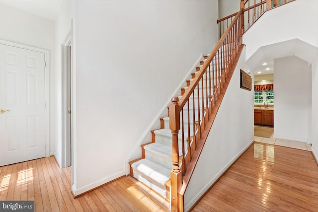 stairs with hardwood / wood-style floors, a high ceiling, and sink