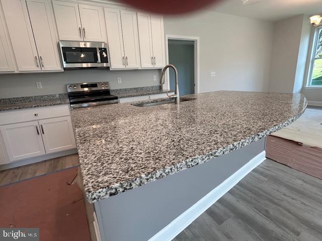 kitchen with stone counters, sink, white cabinets, and appliances with stainless steel finishes