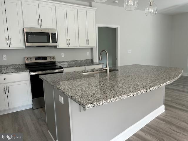 kitchen with white cabinets, a center island with sink, sink, and appliances with stainless steel finishes