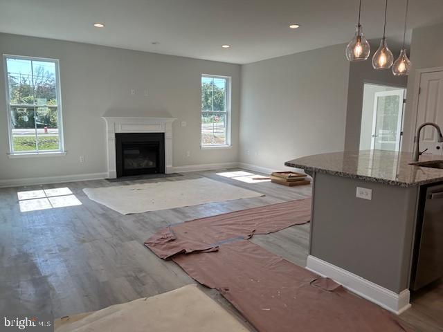 interior space with pendant lighting, dishwasher, stone counters, sink, and a wealth of natural light