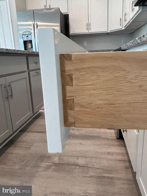 interior space with white cabinets, stainless steel fridge with ice dispenser, and gray cabinets