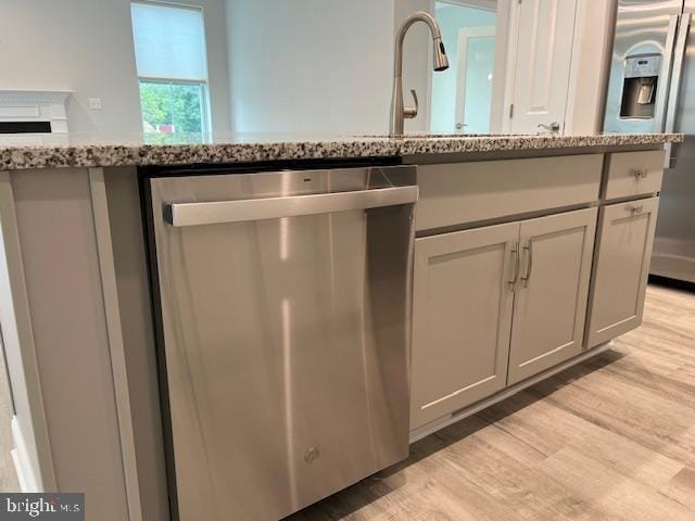 details featuring light stone counters, sink, stainless steel appliances, and light hardwood / wood-style floors