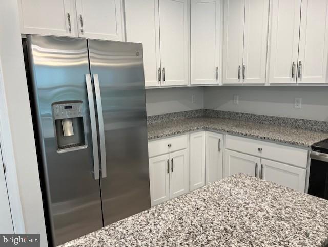 kitchen featuring light stone countertops, white cabinetry, and stainless steel appliances