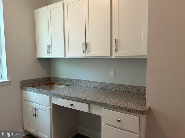 kitchen featuring light stone counters and white cabinets