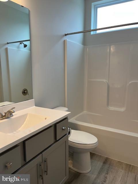 full bathroom with toilet, vanity,  shower combination, and hardwood / wood-style flooring