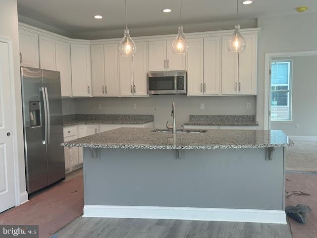 kitchen with pendant lighting, sink, hardwood / wood-style flooring, white cabinetry, and stainless steel appliances