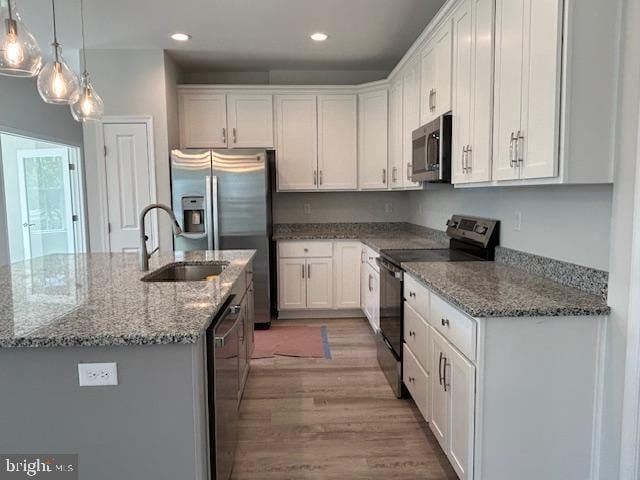 kitchen with white cabinetry, a center island with sink, stainless steel appliances, and decorative light fixtures