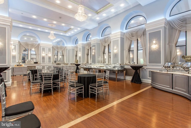 dining area featuring a towering ceiling, wood-type flooring, and crown molding