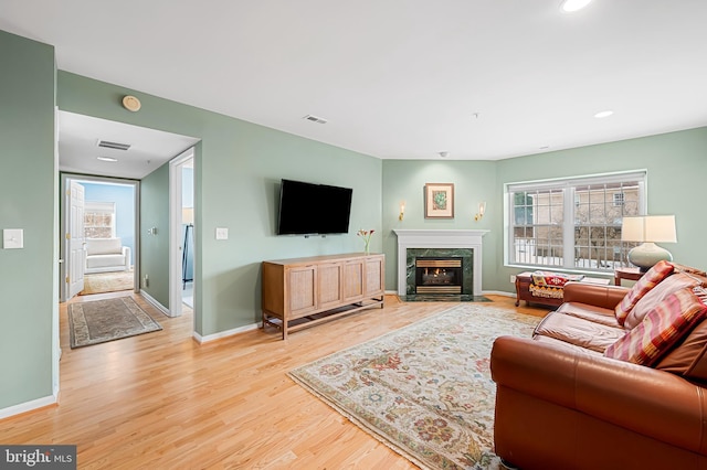 living room with a fireplace and light wood-type flooring